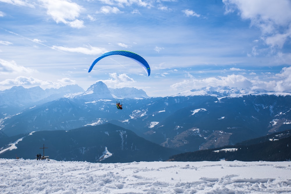 a person paragliding over a snow covered mountain