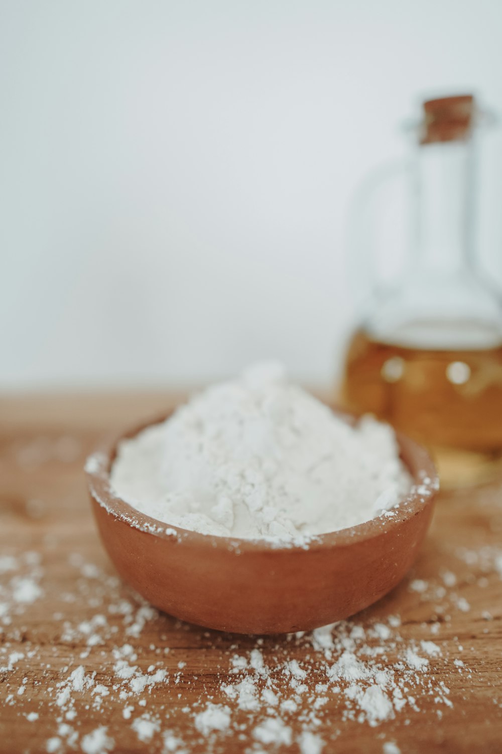 a wooden bowl filled with white powder next to a bottle of honey