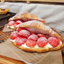 Close-up of assorted filled brioches showcasing chocolate, strawberry, and vanilla fillings on a rustic wooden table.
