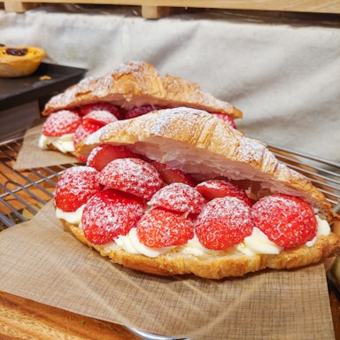 Close-up of assorted filled brioches showcasing chocolate, strawberry, and vanilla fillings on a rustic wooden table.