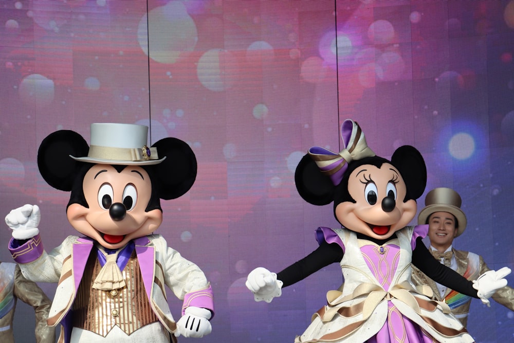 Un couple de personnes debout devant Mickey Mouse