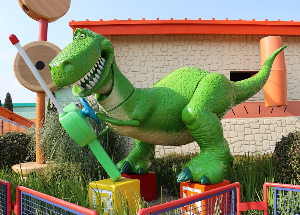 a large green dinosaur statue in front of a building