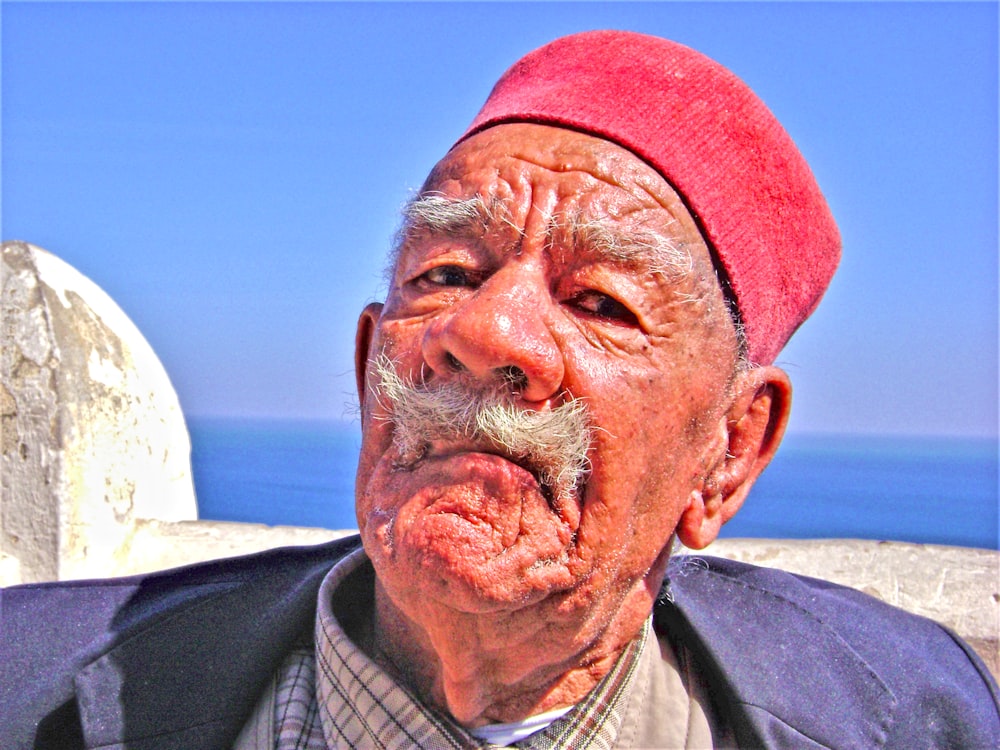 Un vieil homme avec une moustache et un chapeau rouge