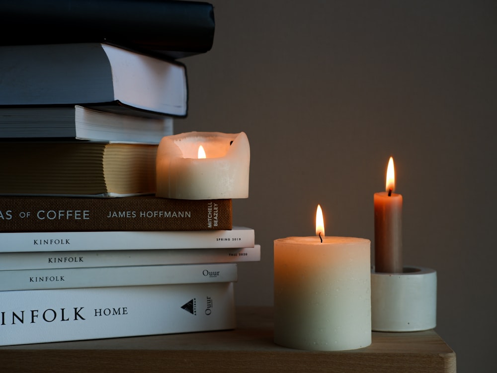a stack of books sitting next to a lit candle