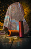 Vibrant patterned silk fabrics draped over a wooden table.