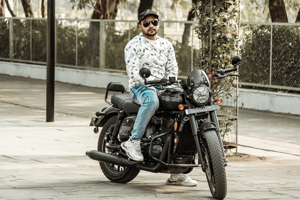 a man sitting on a motorcycle on a sidewalk