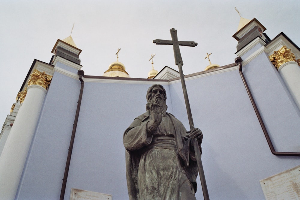 a statue of a man holding a cross in front of a building