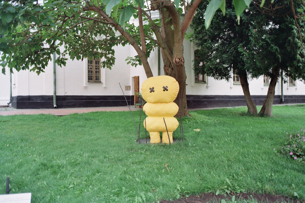 a large yellow stuffed animal sitting in the grass