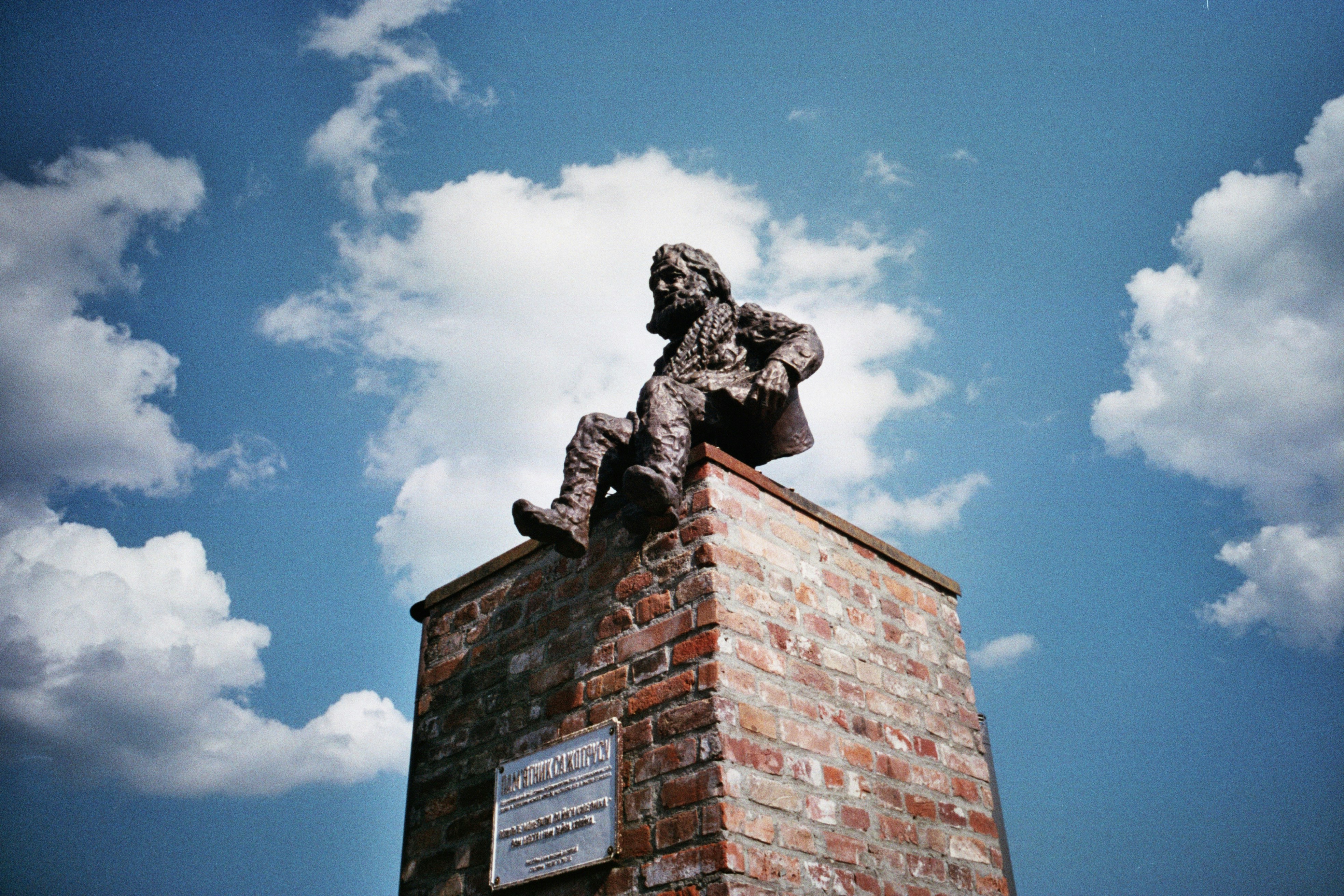 a statue of a man sitting on top of a brick wall