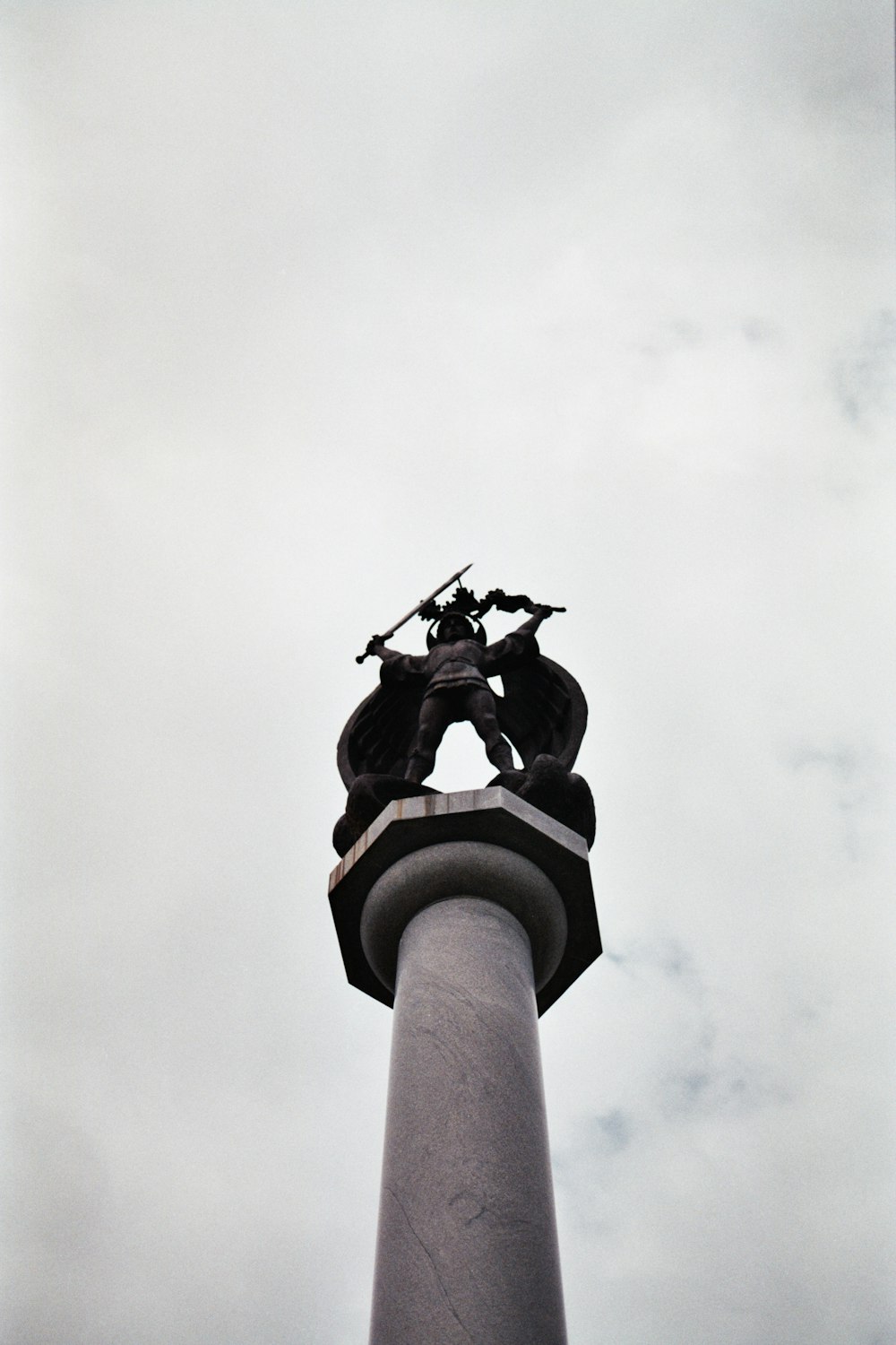 a statue on top of a pole with a sky background