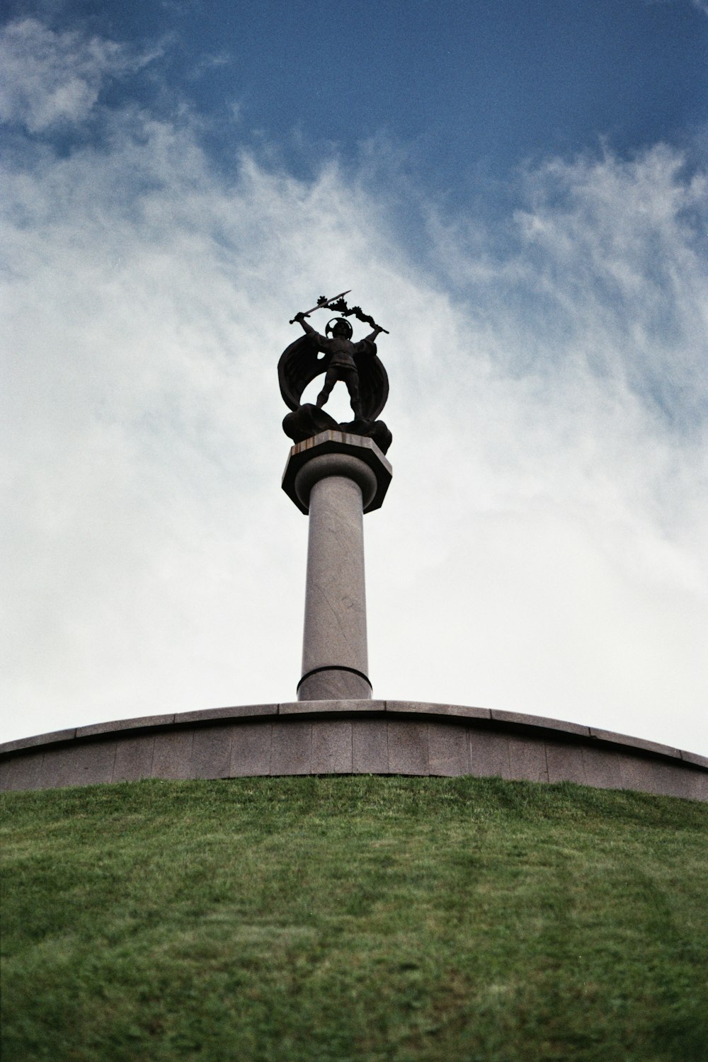 a statue on top of a hill with a sky background