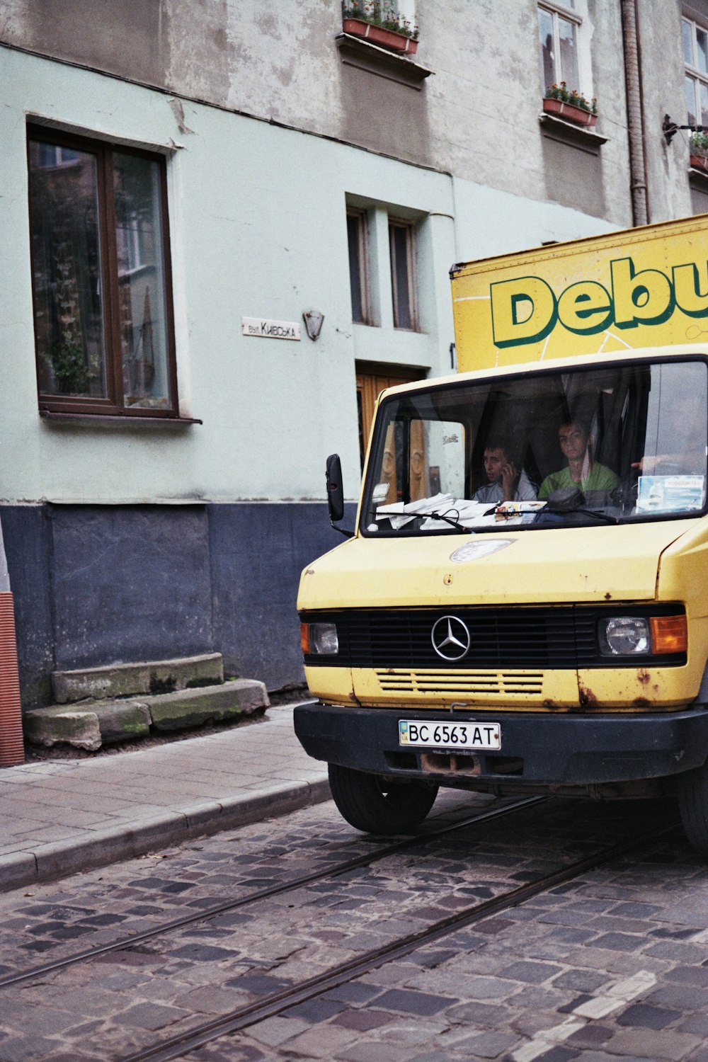 a yellow delivery truck driving down a street
