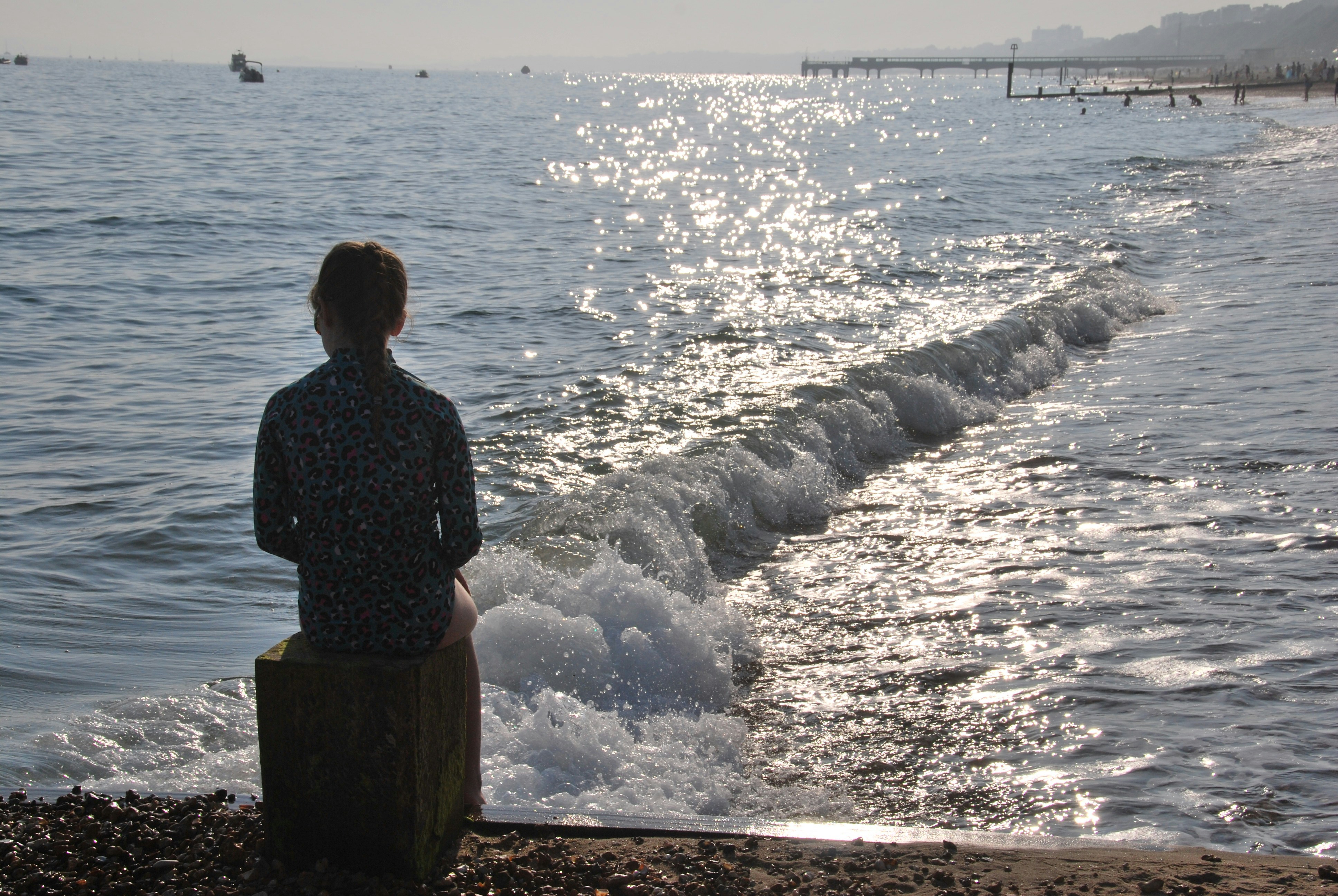 A woman standing on a beach next to the ocean photo – Free Sunset beach ...