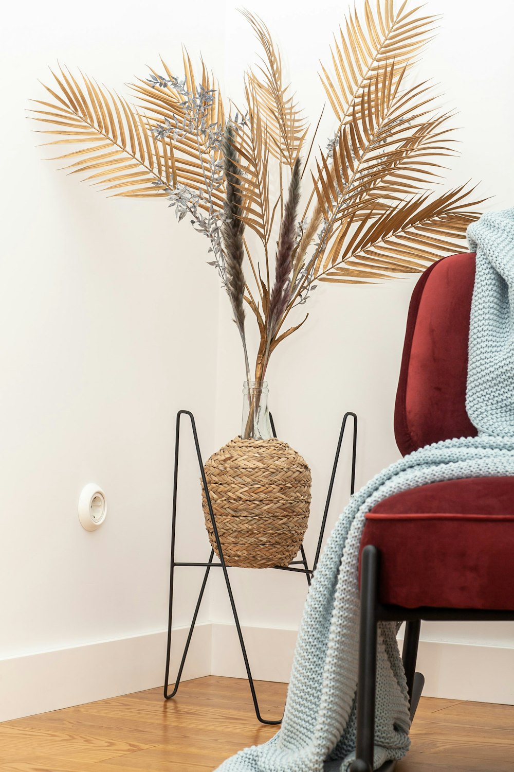a chair with a blanket on it next to a potted plant