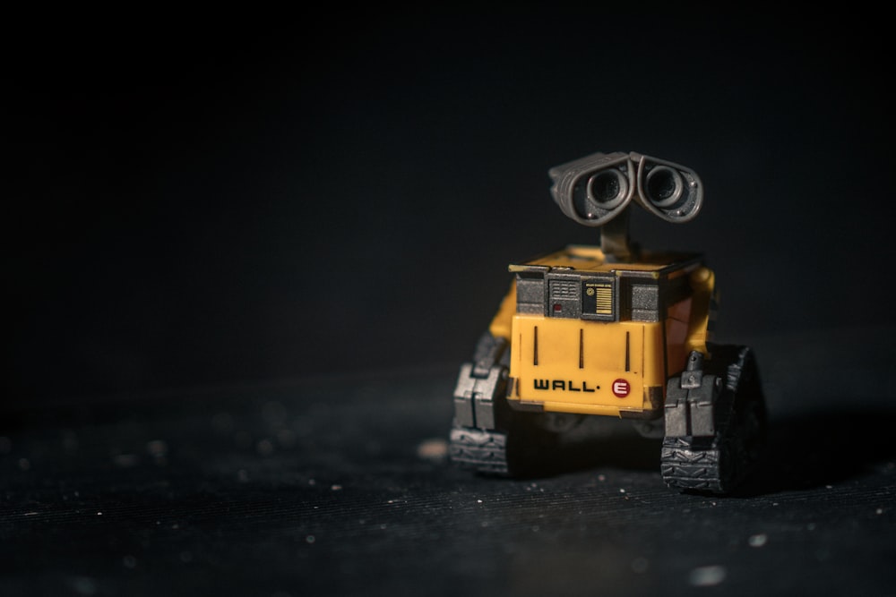 a small yellow and black robot on a black surface