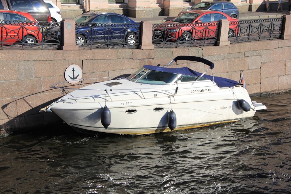 a white boat sitting in the water next to a wall