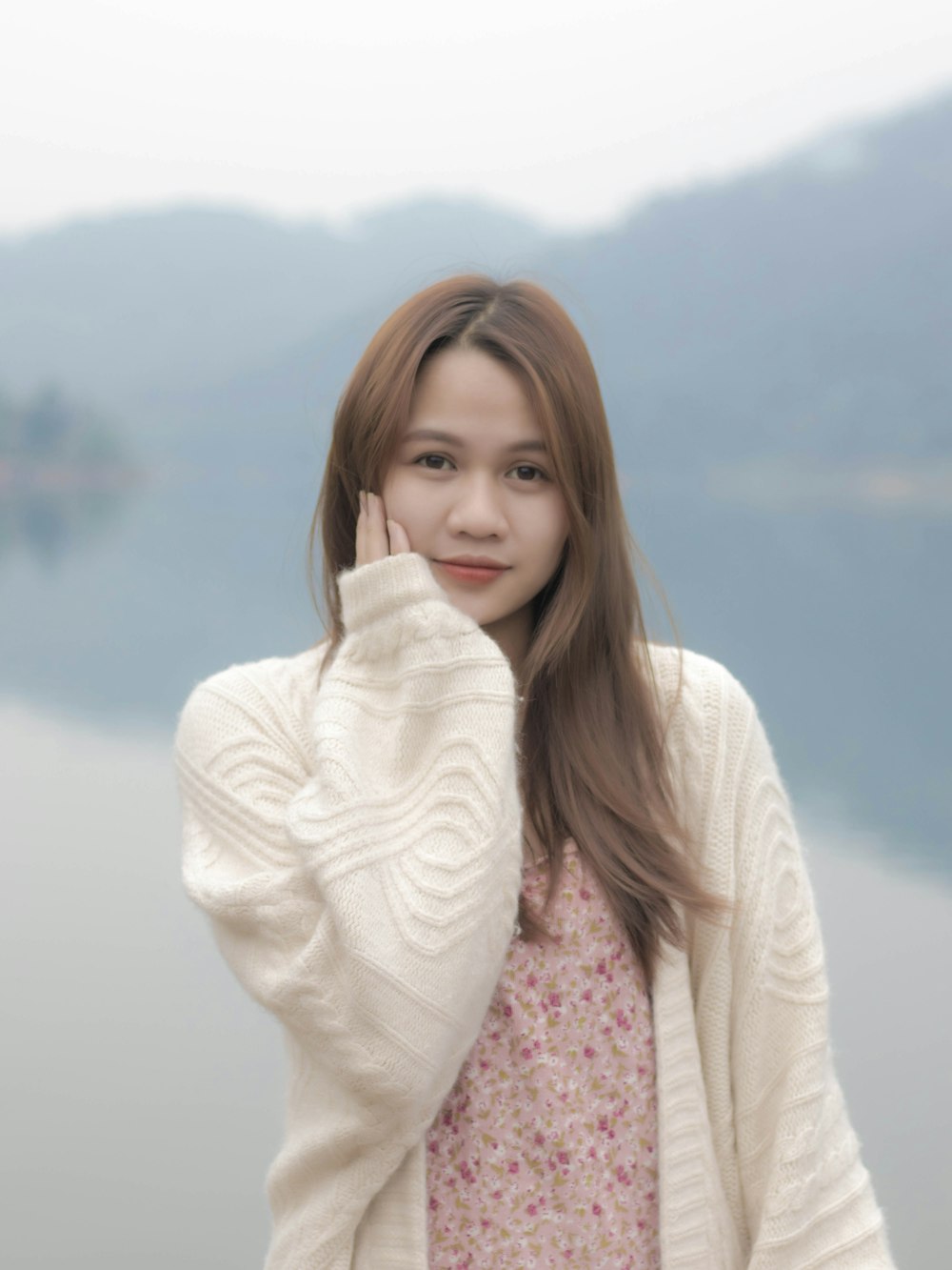 a young woman posing for a picture in front of a body of water