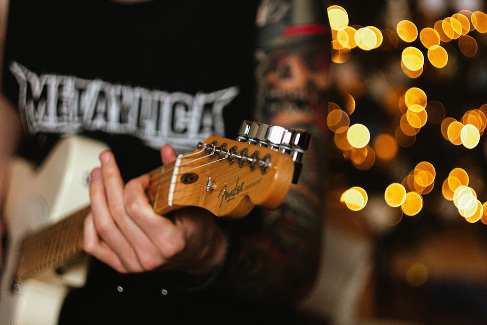 a man playing a guitar in front of a christmas tree