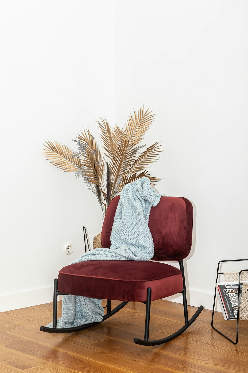 a chair with a blanket on it next to a potted plant