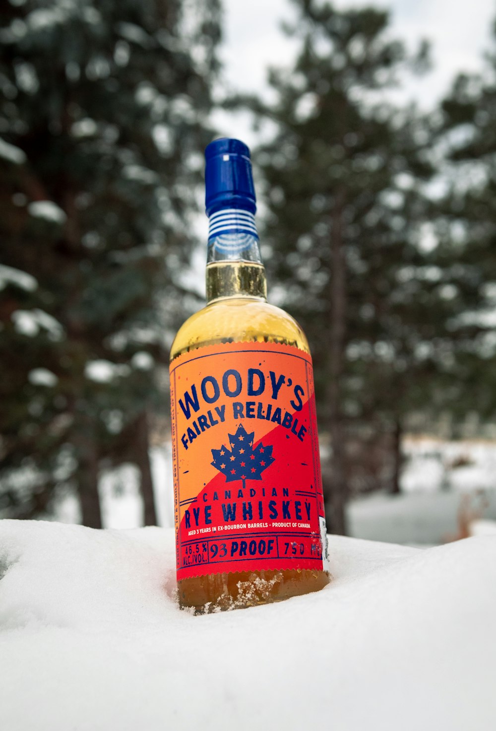 a bottle of woody's early release in the snow