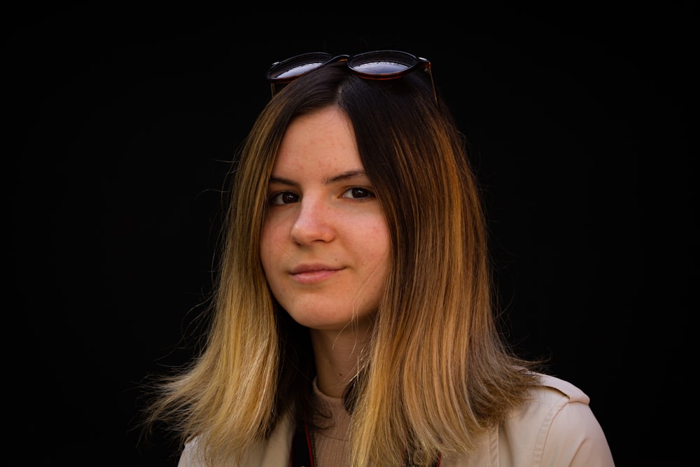 a woman with sunglasses on her head looking at the camera