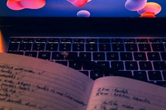 an open book sitting on top of a laptop computer