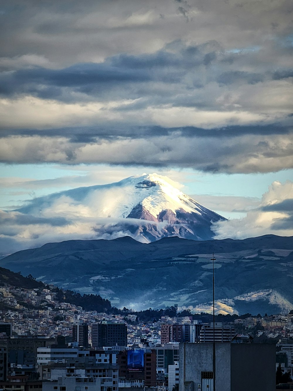 a large snow covered mountain towering over a city