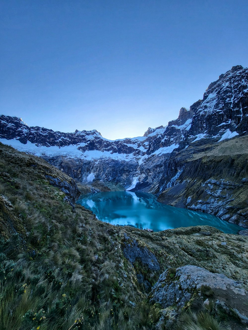 a blue lake surrounded by snow covered mountains