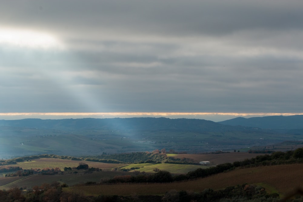 the sun shines through the clouds over a valley