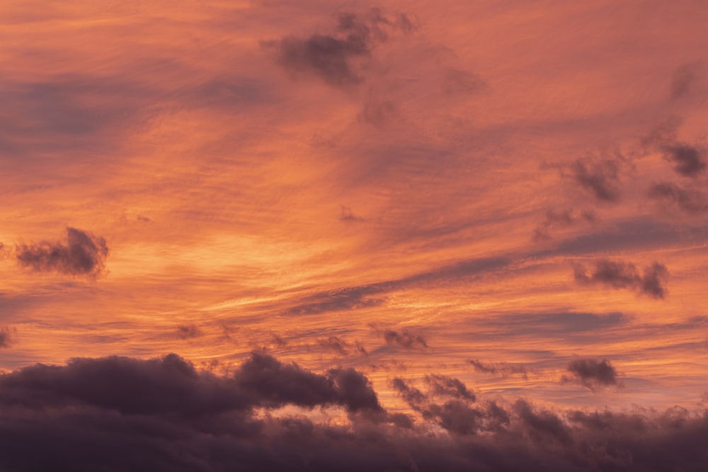 a plane flying in the sky at sunset