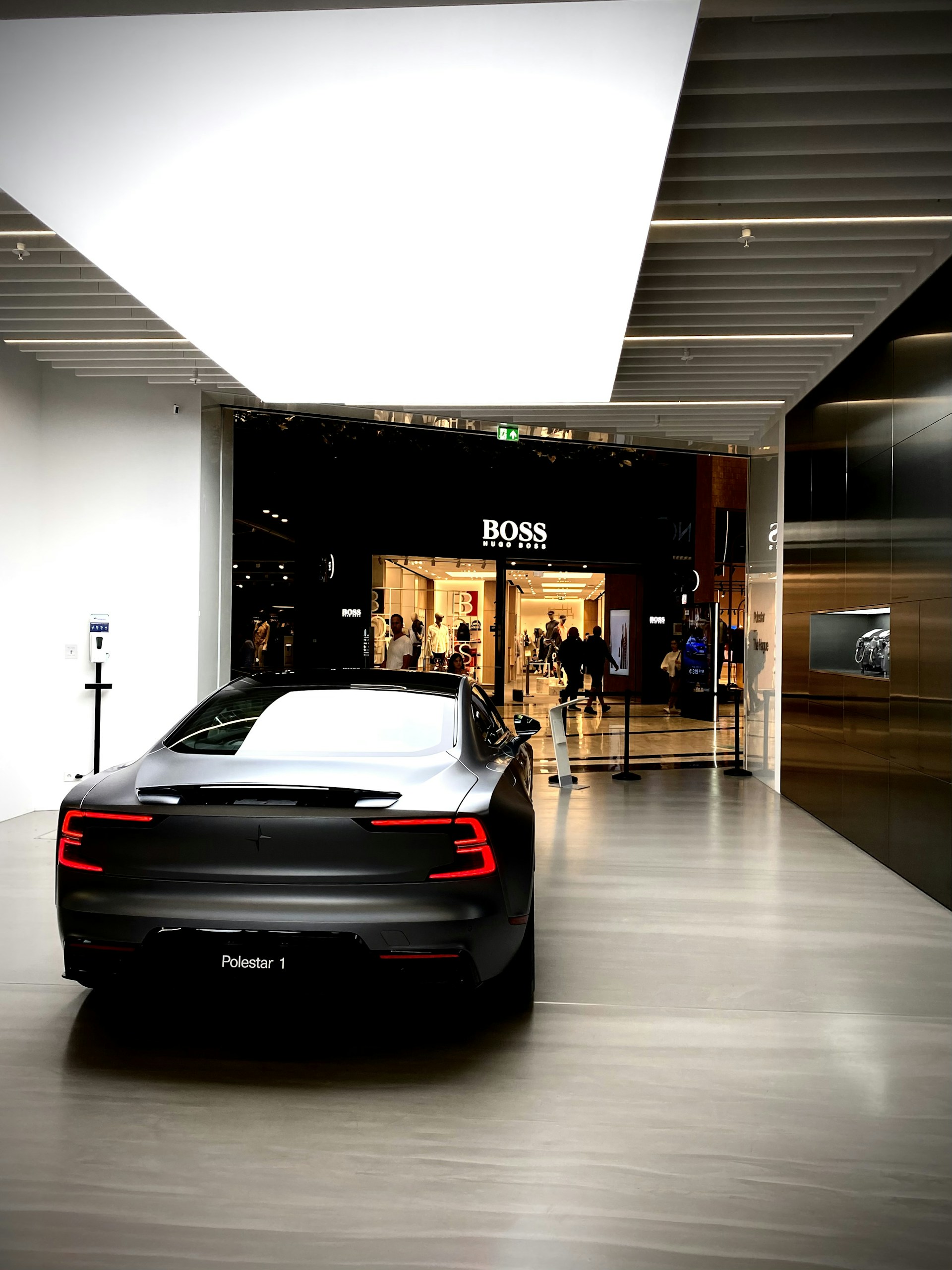 A sleek luxury car parked beside a modern fashion boutique, reflecting the blend of style and speed.