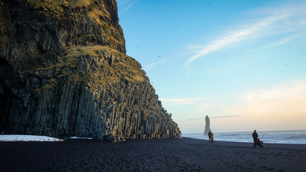 a couple of people standing on top of a sandy beach