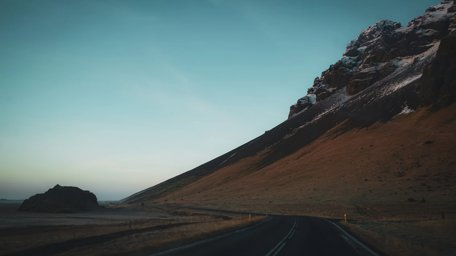 An open Icelandic road with a mountain beyond