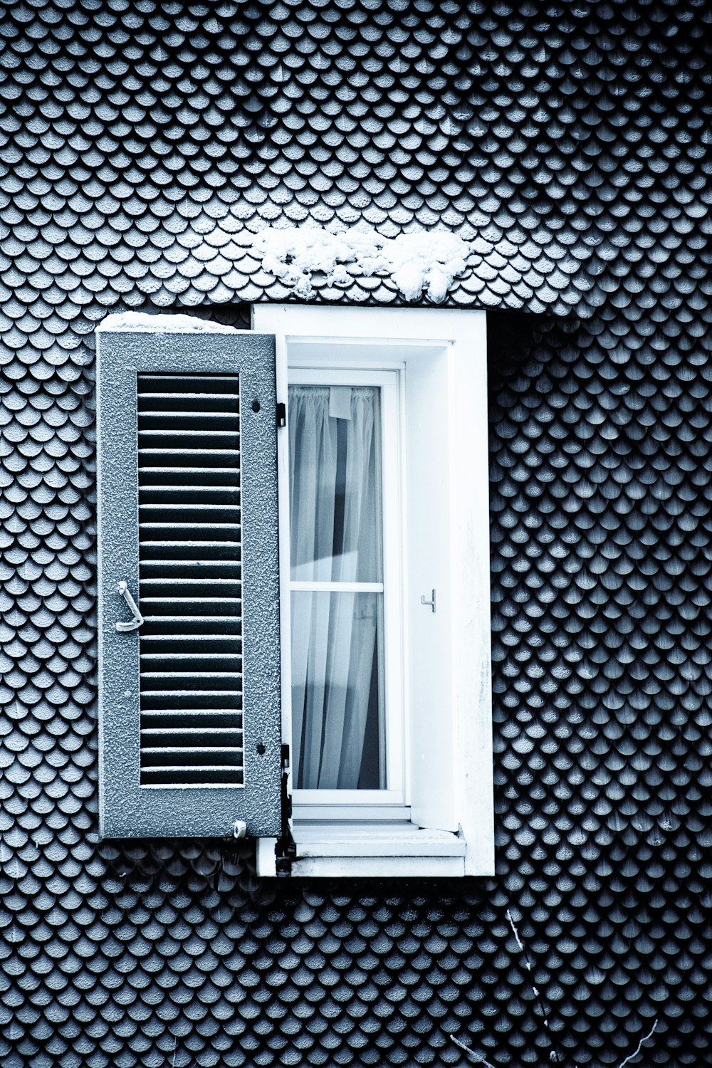 a black and white photo of a window with shutters