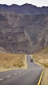 a truck driving down the road in front of a mountain