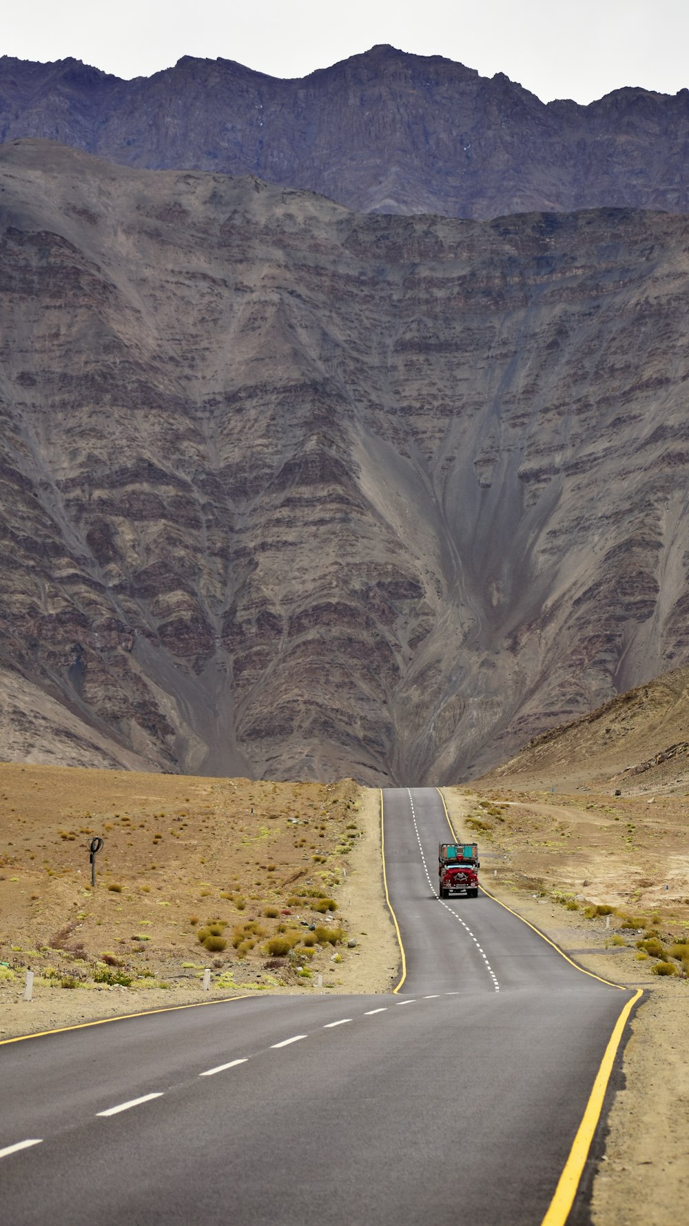 a truck driving down the road in front of a mountain