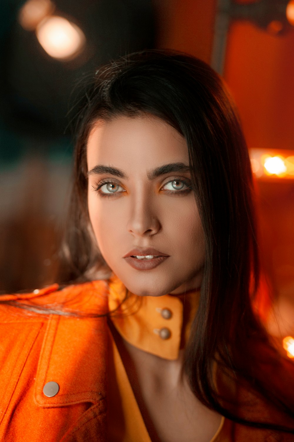 a woman with long hair wearing an orange jacket