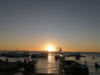 Sunset over the Mediterranean Sea with boats anchored near the shore