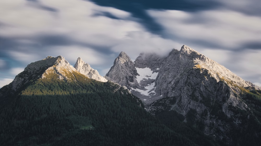 a mountain range covered in snow under a cloudy sky