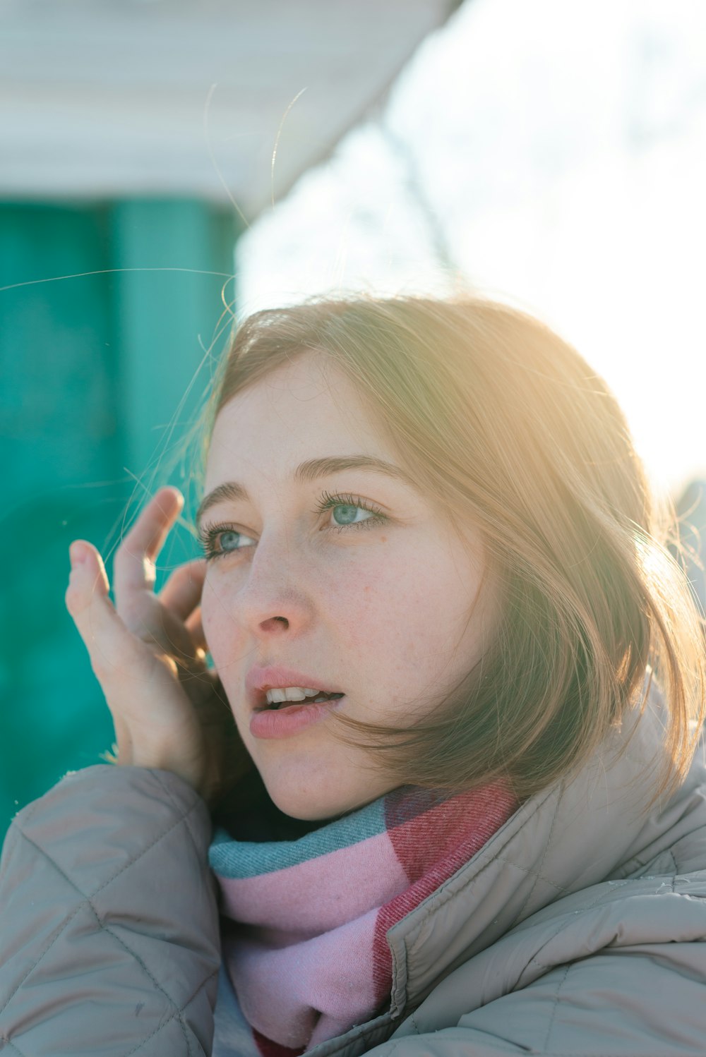 a woman talking on a cell phone while wearing a scarf