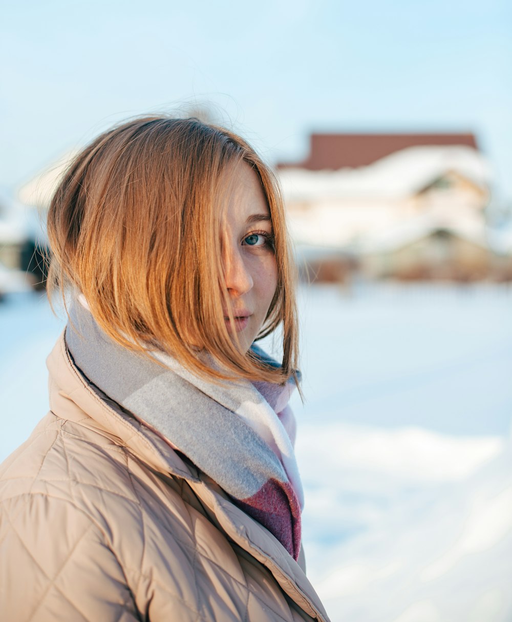 a woman standing in the snow with a scarf around her neck