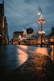 a cobblestone street at night with lights and buildings in the background