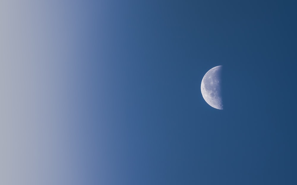 a half moon is seen in a blue sky