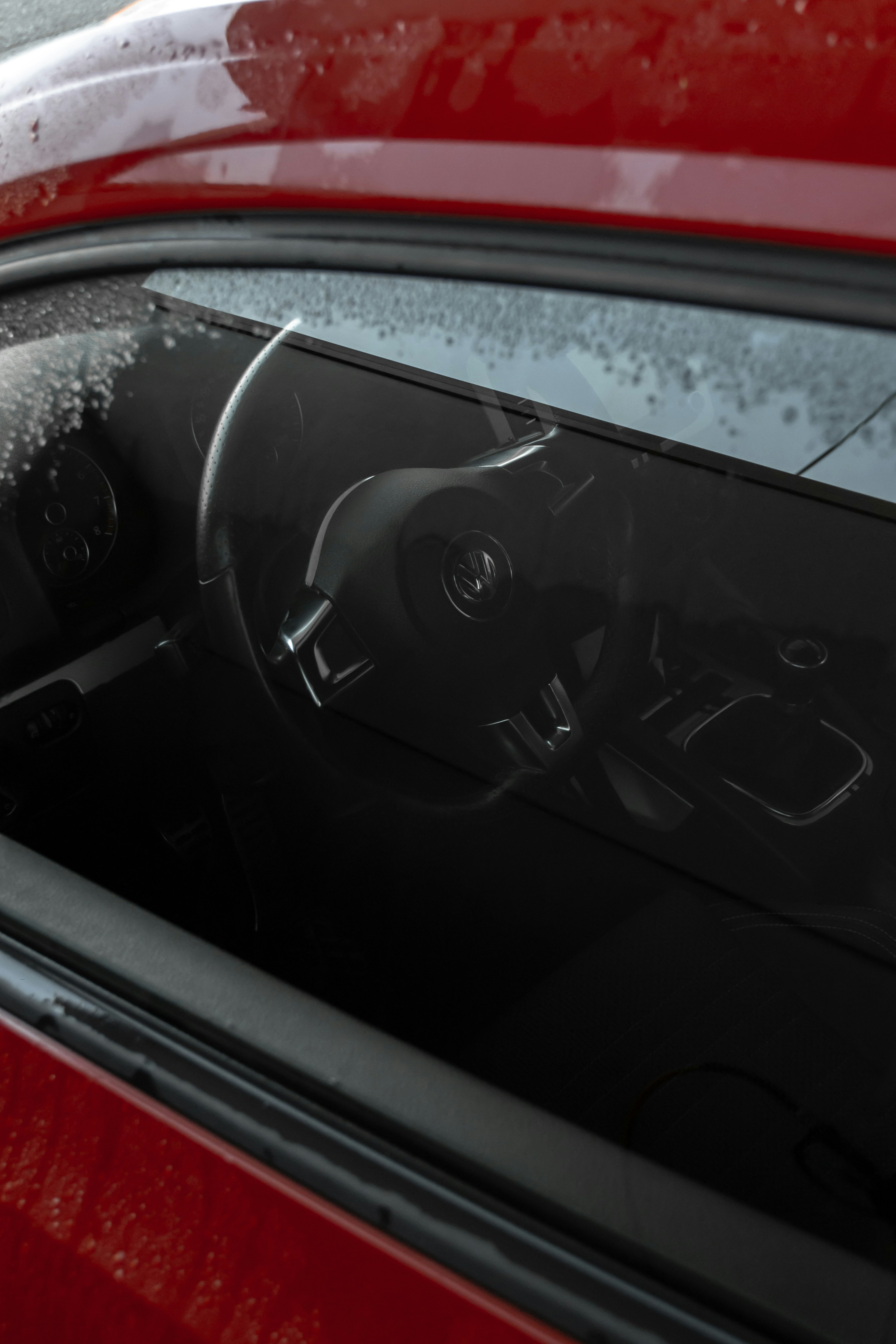 the inside of a red car with rain on the windshield