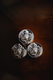 three metal buttons with a lion head on them