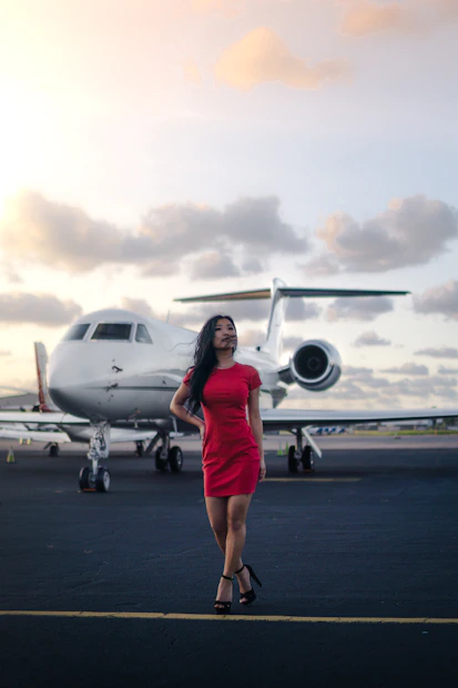 a woman in a red dress standing in front of a plane