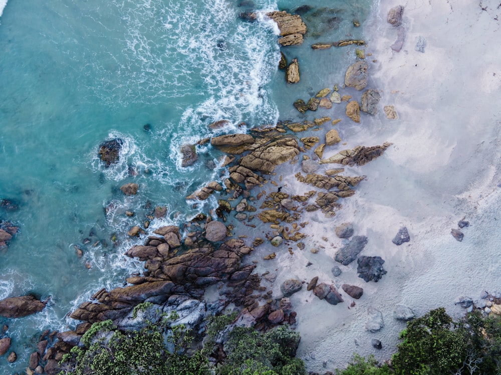 uma vista aérea de uma praia com rochas e água