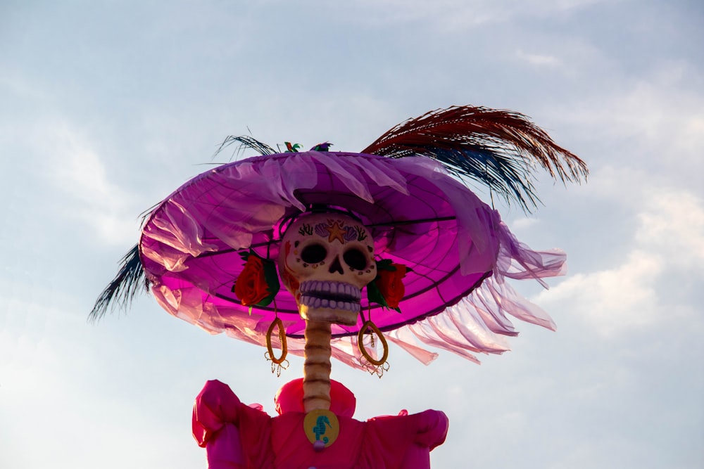a skeleton wearing a purple hat and holding a pink umbrella
