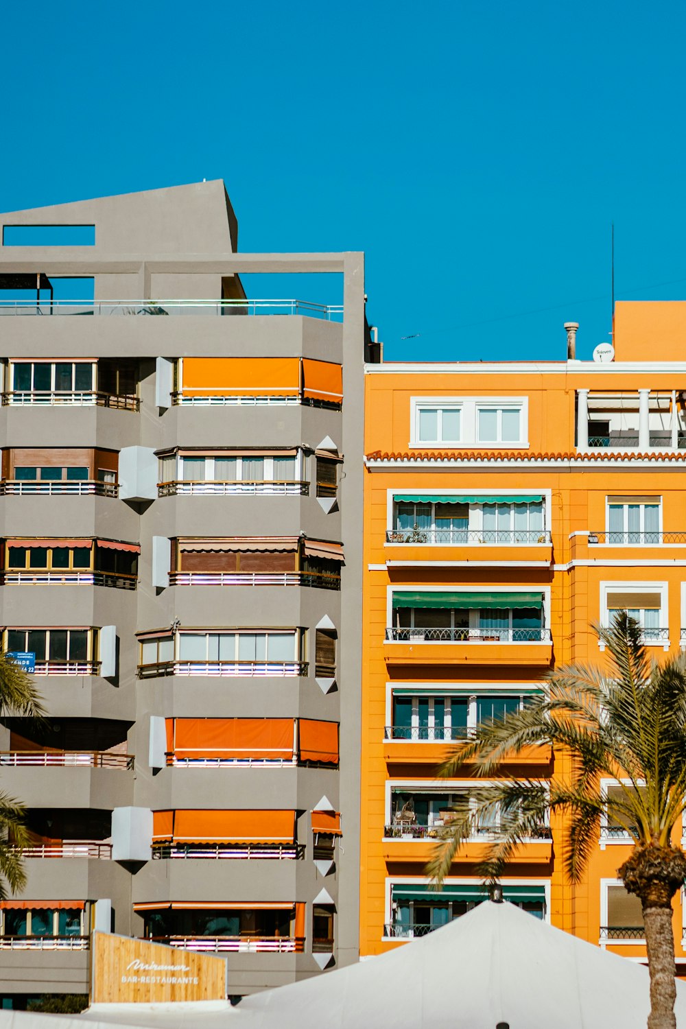 a tall building with balconies and palm trees in front of it