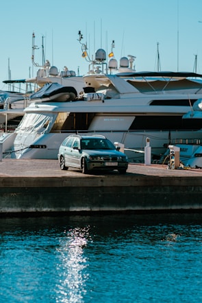 a car parked on a dock next to a boat